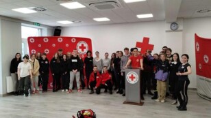 grupa uczniów, nauczycieli i ratowników stoi w sali szkoleniowej